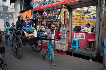 India, West Bengal, Kolkata, A rickshaw driver pulls passengers through the streets.