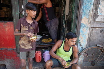 India, West Bengal, Kolkata, A man and boy eat a snack of pani puri and vegetables.