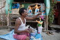India, West Bengal, Kolkata, A craftsman decorates a durga idol in the Kumartuli district.