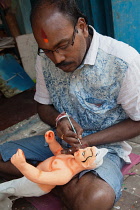 India, West Bengal, Kolkata, A painter adds colour to a durga statue in the Kumartuli district.