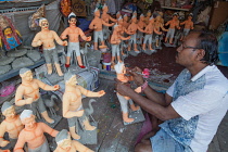 India, West Bengal, Kolkata, A painter adds colour to durga statues in the Kumartuli district.