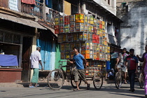 India, West Bengal, Kolkata, A man with a load of tin containers on his cycle-drawn cart.