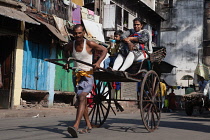 India, West Bengal, Kolkata, A rickshaw driver pulls passengers through the streets.