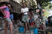 India, West Bengal, Kolkata, Men collect water at a road-side pump.