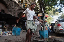 India, West Bengal, Kolkata, A man collects water at a road-side pump.