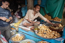 India, West Bengal, Kolkata, A vendor selling snack food including samosas, kachori, and pani puri.