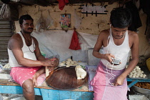 India, West Bengal, Kolkata, A worker at a food hotel in takes a break to use his iphone.