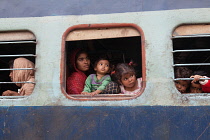 India, West Bengal, Asansol, Passengers at the windows of a train carriage at railway station.