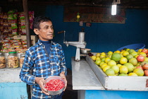 India, West Bengal, Asansol, Portrait of a juice vendor holding a bowl of pomegranate seeds.