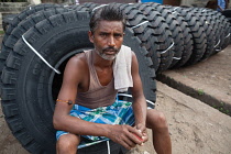 India, West Bengal, Asansol, Portrait of a labourer at a truck tyre retailer.