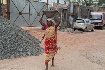 India, West Bengal, Asansol, A female labourer carrying a container of stone chippings on her head.