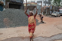 India, West Bengal, Asansol, A female labourer carrying a container of stone chippings on her head.