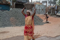 India, West Bengal, Asansol, A female labourer carrying a container of stone chippings on her head.