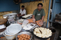 India, West Bengal, Asansol, A man frying samosas and puris at a food hotel.