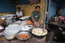 India, West Bengal, Asansol, A man frying samosas and puris at a food hotel.