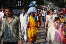 India, West Bengal, Asansol, A woman carries a burden on her head as she walks through the streets.