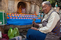 India, Bihar, Bodhgaya, A pilgrim from Tibet with a prayer wheel in front of a statue of the Buddha at the Mahabodhi Temple at Bodh.