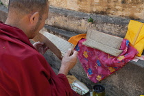 India, Bihar, Bodhgaya, A Buddhist monk reading a Tibetan prayer card at the Mahabodhi Temple at Bodh.