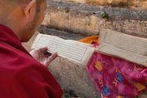 India, Bihar, Bodhgaya, A Buddhist monk reading a Tibetan prayer card at the Mahabodhi Temple at Bodh.