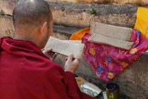 India, Bihar, Bodhgaya, A Buddhist monk reading a Tibetan prayer card at the Mahabodhi Temple at Bodh.