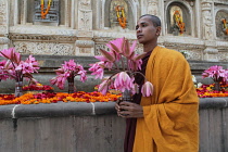 India, Bihar, Bodhgaya, A monk with a lotus flower offering at the Mahabodhi Temple in Bodh.