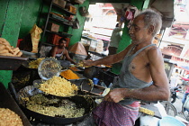 India, Bihar, Gaya, A cook frying chat and namkeen at a food hotel.