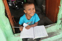 India, Bihar, Gaya, A smiling boy completing homework.