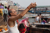 India, Uttar Pradesh, Varanasi, Pilgrim praying at Dashashwamedh Ghat beside the River Ganges.