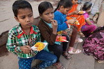 India, Uttar Pradesh, Varanasi, Children eat a snack of bhel puri on the ghats.