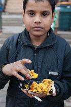 India, Uttar Pradesh, Varanasi, A boy eats street food.