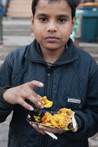 India, Uttar Pradesh, Varanasi, A boy eats street food.