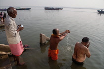 India, Uttar Pradesh, Varanasi, Pilgrims pray at the River Ganges beside Kedar Ghat.
