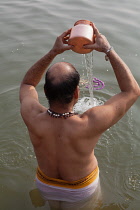 India, Uttar Pradesh, Varanasi, A pilgrim prays in the River Ganges.