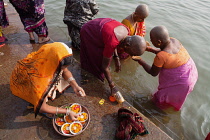 India, Uttar Pradesh, Varanasi, Female pilgrims pray and make offerings at the River Ganges.