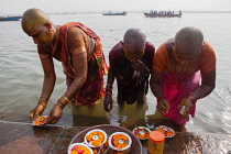 India, Uttar Pradesh, Varanasi, Female pilgrims pray and make offerings at the River Ganges.