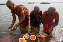 India, Uttar Pradesh, Varanasi, Female pilgrims pray and make offerings at the River Ganges.