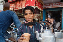 India, Uttar Pradesh, Varanasi, A chai boy serving tea.