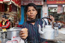 India, Uttar Pradesh, Varanasi, A chai boy serving tea.