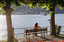 Italy, Lombardy, Lake Como, Bellagio, person on bench at sunset.