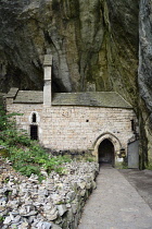 France, Lozere, St Chely du Tarn, Gorges du Tarn, Historic Chapelle de Notre-Dame de Cenaret set in a niche under the cliffs, Small cairns built by visitors, over the years, in the foreground