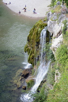 France, Lozere, St Chely du Tarn, Gorges du Tarn, Waterfall where mountain stream that runs through the village cascades into the Tarn, Holidaymakers on the beach in the background.