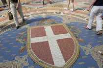 Italy, Lombardy, Milan, Galleria Vittorio Emanuele II floor mosaic (Savoy coat of arms)  with shoppers.