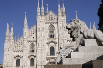 Italy, Lombardy, Milan, lion from monument to Vittorio Emanuelle II with Duomo facade, Piazza Duomo.