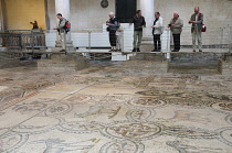 Italy, Friuli Venezia Giulia, Aquileia, visitor walking on floating walkway above mosaic flooring.