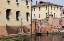 Italy, Veneto, Treviso, canal & building with fishing wall painting.