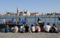 Italy, Veneto, Venice, gondolas & people sitting on waterside at Il Molo.