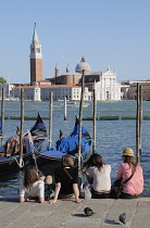 Italy, Veneto, Venice, gondolas & people sitting on waterside at Il Molo.