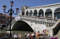 Italy, Veneto, Venice, Rialto bridge over the Grand Canal with cafe in foreground.
