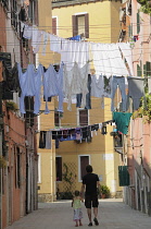 Italy, Veneto, Venice, Arsenale, narrow strees with washing & child & father walking.