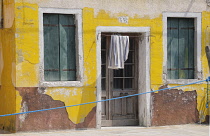 Italy, Veneto, Venice, Burano, faded yellow house.